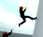 Two fundraisers in helmets and harnesses abseiling down the side of a building